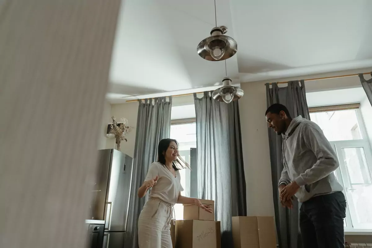Paar trägt einen Karton gemeinsam durch die Wohnung