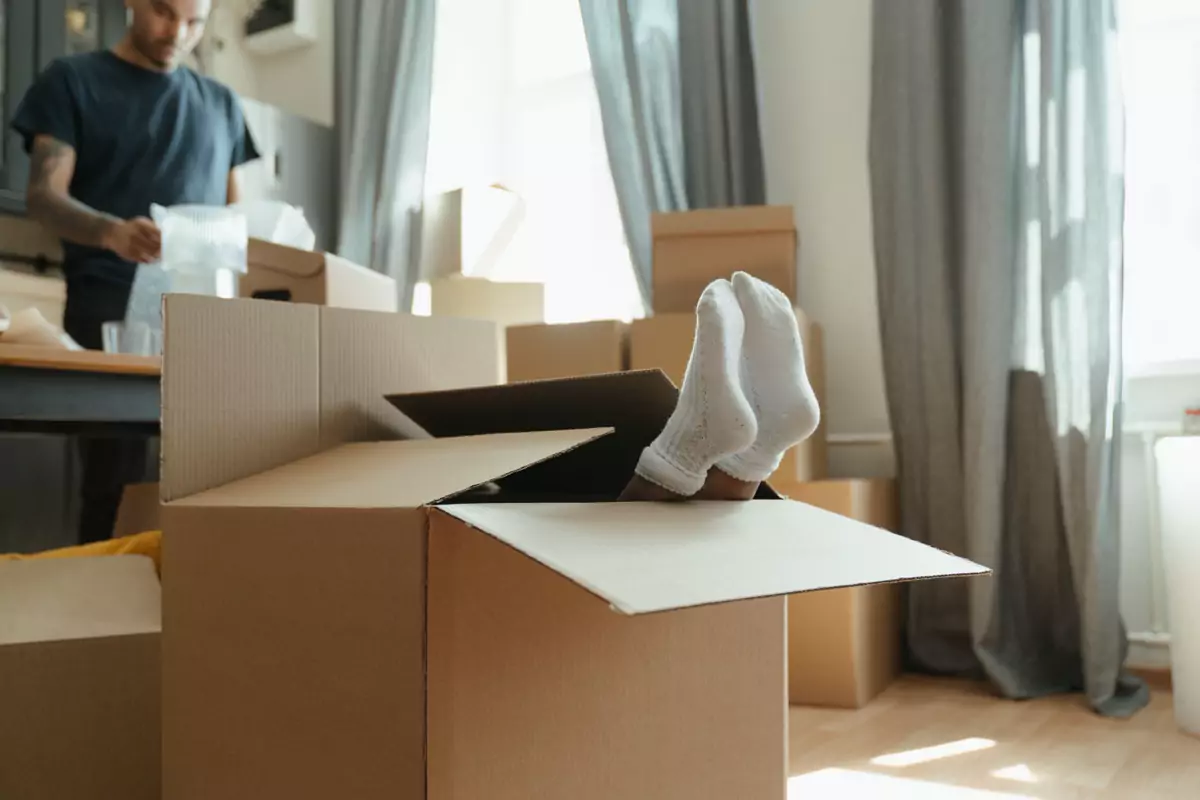 Umziehende Person sitzt zwischen geöffneten und gepackten Kartons