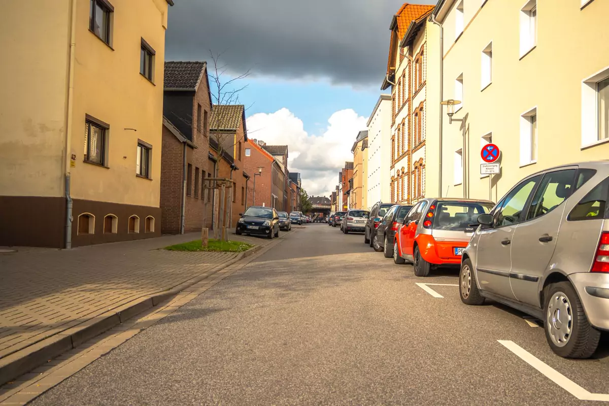 Wohnstraße mit Häuserzeile und abgestellten Fahrzeugen