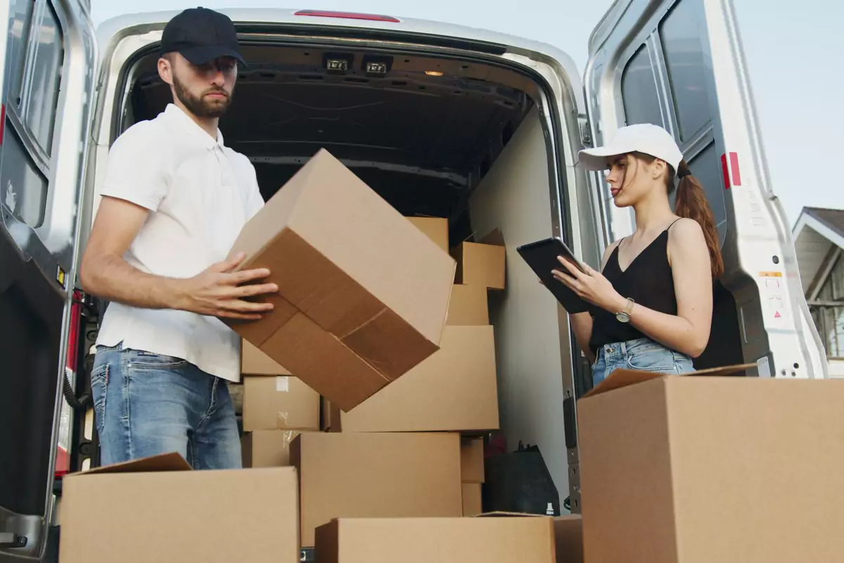 Umzugshelfer übergibt Kartons am geöffneten Transporter