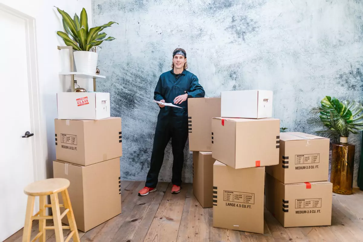 Umzugshelfer steht mit gepackten Kartons vor einer Wohnung
