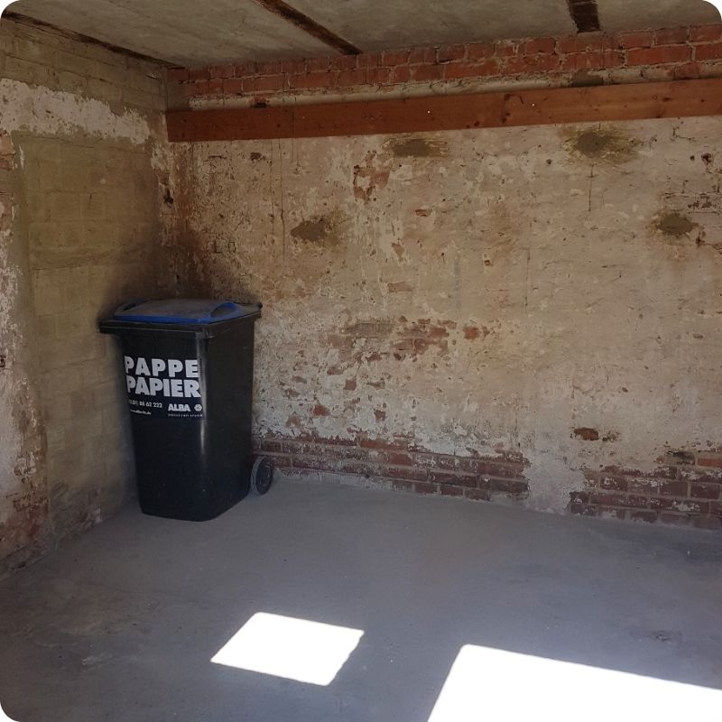 Leerer Kellerraum mit Papiertonne nach Entrümpelung