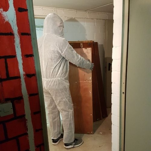 Mitarbeiter CityTransportWob im Schutzanzug entsorgt einen Schrank